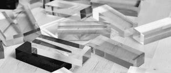 Several clear acrylic rectangular blocks are scattered on a light wooden surface, illustrating the building blocks of modern enterprise solutions and AI innovation.