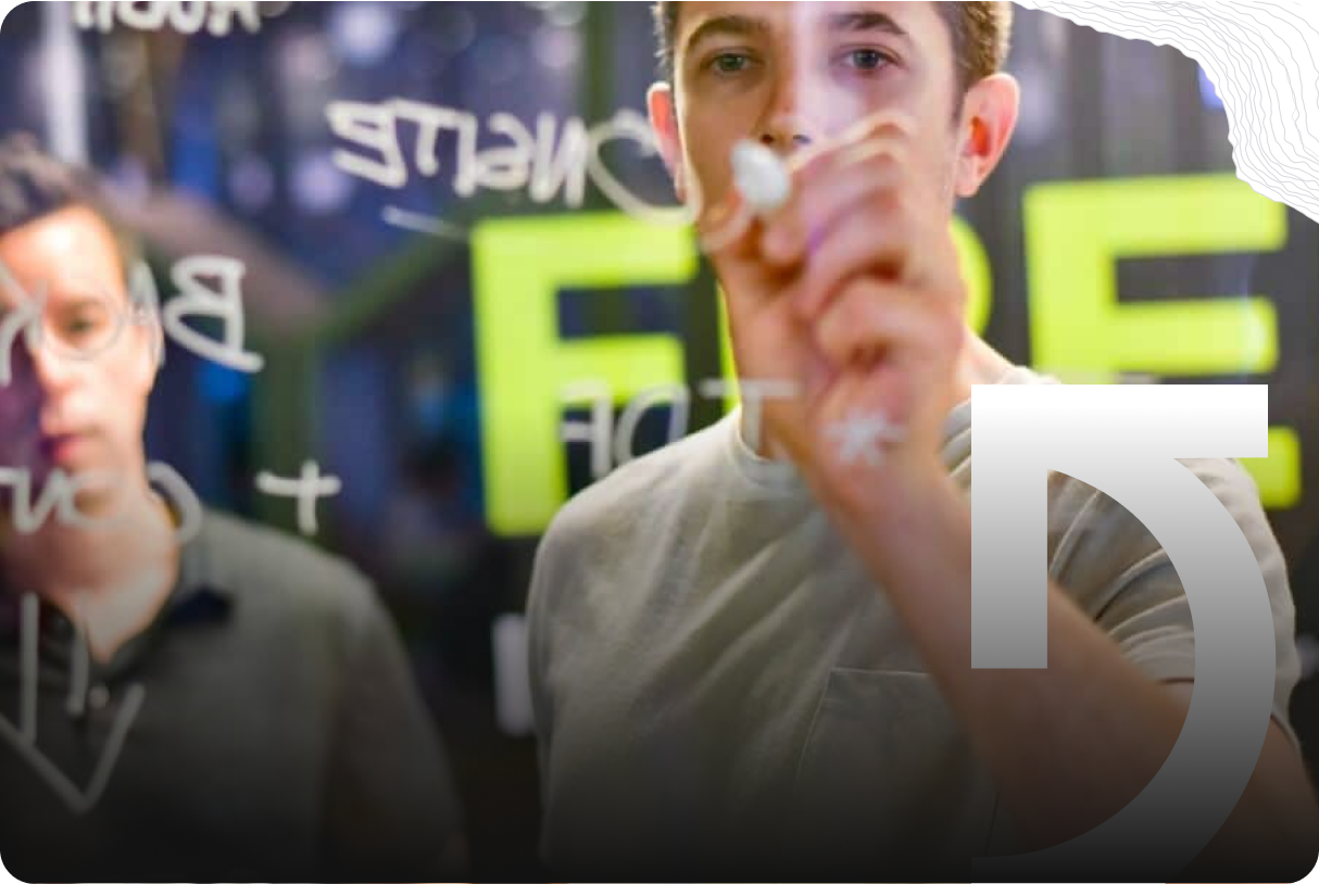 Two people are standing behind a transparent board, with one writing mathematical or scientific formulas on it using a white marker, illustrating the beginnings of many success stories in science and innovation.