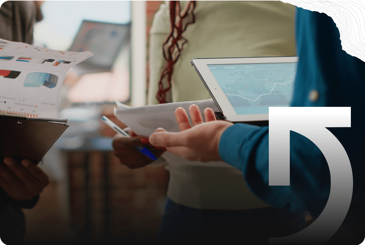 Three people review graphs and charts on paper and a tablet, discussing data and sharing Success Stories in an office setting.